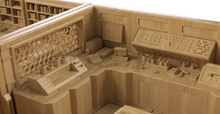 Load image into Gallery viewer, A close-up of a miniature science control room or cockpit model, showing detailed paneling, console surfaces, shelving, and small decorative elements in a uniform light wood tone.